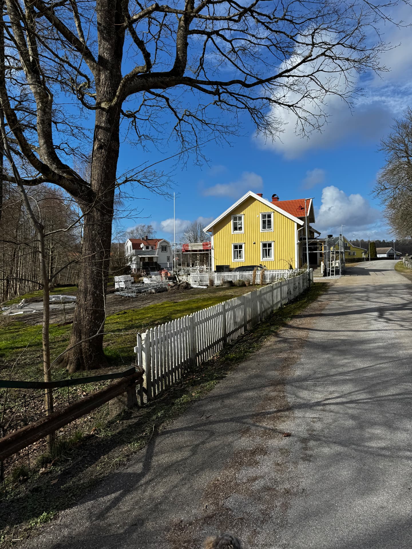 Tomt i Stenungsund före finplanering – schaktad mark och byggmaterial vid gult trähus